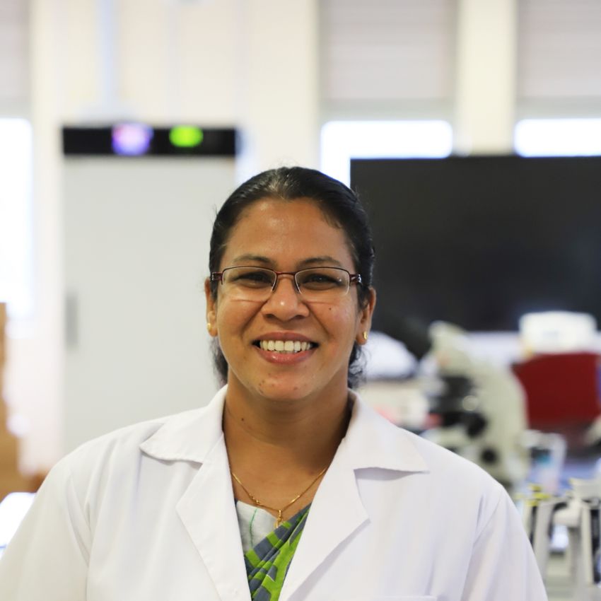 Photograph of Asha Wijegunawardana, an animal biotechnologist at the Rajarat University of Sri Lanka. Wijegunawardana is wearing a white lab coat and has rectangular-framed glasses and dark hair pulled away from her face. She is smiling at the camera. Photograph of Asha Wijegunawardana, an animal biotechnologist at the Rajarat University of Sri Lanka. Wijegunawardana is wearing a white lab coat and has rectangular-framed glasses and dark hair pulled away from her face. She is smiling at the camera.