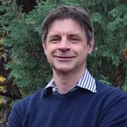 Photograph of Neil Marsh, a biochemist at the University of Michigan. Marsh is standing in front of green leaves and is wearing a blue shirt with a blue and white striped collar. He has short brown hair and is smiling at the camera. Photograph of Neil Marsh, a biochemist at the University of Michigan. Marsh is standing in front of green leaves and is wearing a blue shirt with a blue and white striped collar. He has short brown hair and is smiling at the camera.