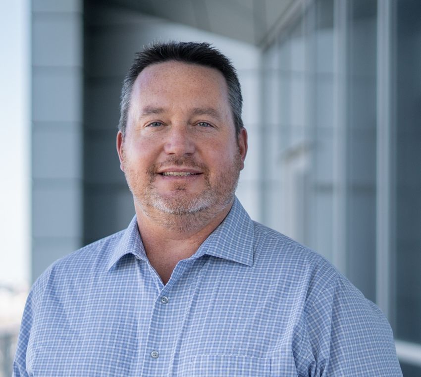Richard DiPaolo, wearing a white and blue checkered shirt, slightly smiles at the camera in front of a blurred background. Richard DiPaolo, wearing a white and blue checkered shirt, slightly smiles at the camera in front of a blurred background.