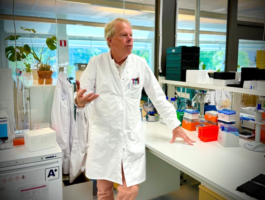Mathias Uhlén, a protein scientist at KTH Royal Institute of Technology, stands at a lab bench. He is wearing a white lab coat and looking off of the camera and gesturing with one hand in mid-conversation. Mathias Uhlén, a protein scientist at KTH Royal Institute of Technology, stands at a lab bench. He is wearing a white lab coat and looking off of the camera and gesturing with one hand in mid-conversation.