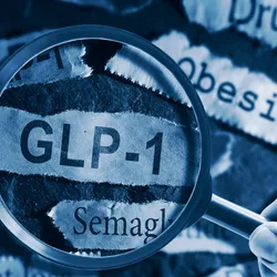 A hand holds a magnifying glass over a strip of paper that says ‘GLP-1’. Surrounding strips of paper have words such as ‘weight loss’, ‘semaglutide’, and ‘obesity’.
