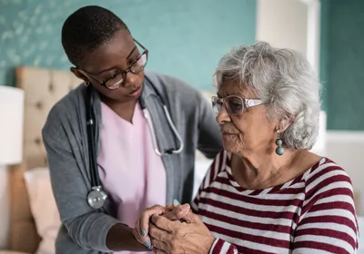 A medical caregiver holds the hand of an elderly patient A medical caregiver holds the hand of an elderly patient