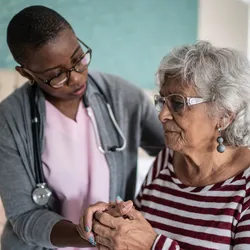 A medical caregiver holds the hand of an elderly patient A medical caregiver holds the hand of an elderly patient