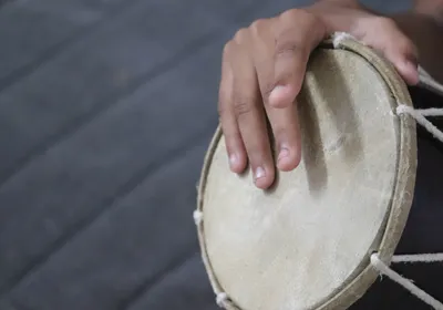 Fingers on a person’s right hand tap on a drum, symbolizing how people’s brains synchronize their movements to musical rhythm. Fingers on a person’s right hand tap on a drum, symbolizing how people’s brains synchronize their movements to musical rhythm.