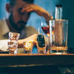 Man sitting at the bar counter alone, seems to be binge drinking. Therapeutics developed based on neurons activated in response to binge drinking could help treat such compulsive drinking.
