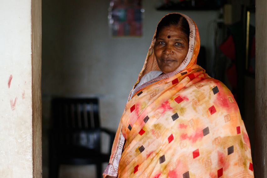 Vimal Chokake stands in a doorway. She wears an orange-colored dress. Vimal Chokake stands in a doorway. She wears an orange-colored dress.