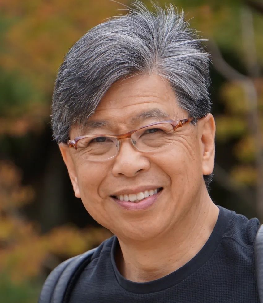 Edison Liu, wearing glasses and a black tee, smiles at the camera. Edison Liu, wearing glasses and a black tee, smiles at the camera.