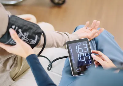 A caregiver checking a patient’s blood pressure and heart rate with a cuff and monitor. A caregiver checking a patient’s blood pressure and heart rate with a cuff and monitor.