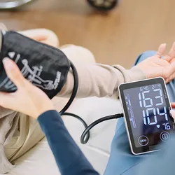 A caregiver checking a patient’s blood pressure and heart rate with a cuff and monitor.