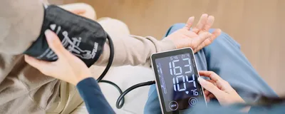 A caregiver checking a patient’s blood pressure and heart rate with a cuff and monitor. A caregiver checking a patient’s blood pressure and heart rate with a cuff and monitor.