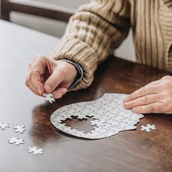 Cropped view of senior man playing with puzzles, indicative of dementia risk.