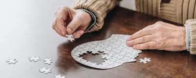 Cropped view of senior man playing with puzzles, indicative of dementia risk.