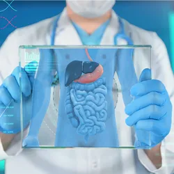 A doctor in a white coat, blue gloves, and surgical mask holds a clear screen showing a gastrointestinal tract and some medical data. 