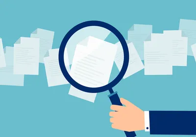 A magnifying glass held against paper illustrates the academic peer review process. A magnifying glass held against paper illustrates the academic peer review process.