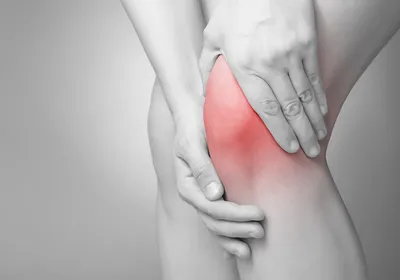 Two hands massaging a knee, indicating pain.