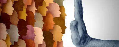 Representative image of travel bans. One the left are silhouettes of human faces in colors ranging from cream to tan to brown. A hand extending from the right is held up in a “stop” signal in front of them in the middle of the image. Representative image of travel bans. One the left are silhouettes of human faces in colors ranging from cream to tan to brown. A hand extending from the right is held up in a “stop” signal in front of them in the middle of the image.