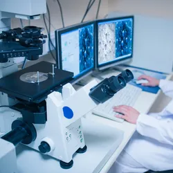 A scientist analyzing a specimen under an electron microscope, carefully observing the intricate molecular structures.