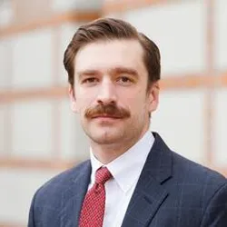 Kenneth Evans wears a dark suit with a red tie.