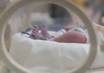 Image of an infant’s feet that are visible in a hospital incubator. Image of an infant’s feet that are visible in a hospital incubator.