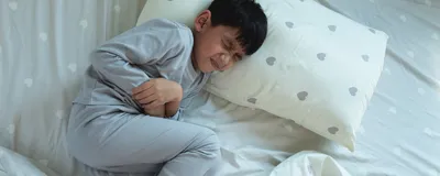 Boy lying in bed with a stomachache, signifying gastroenteritis caused due to human astroviruses. Boy lying in bed with a stomachache, signifying gastroenteritis caused due to human astroviruses.