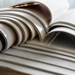 Scientific journals sit open on top of each other in a stack.
