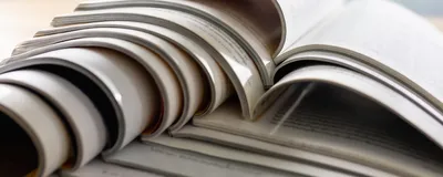 Scientific journals sit open on top of each other in a stack.