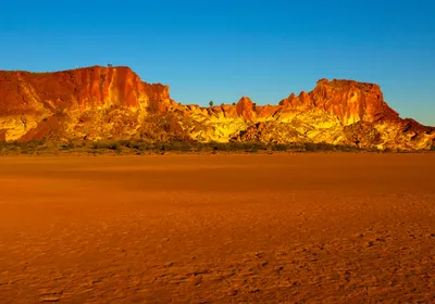A landscape shot of Rainbow Valley, southwest of Alice Springs, in Australia’s Northern Territory. Spectacular red and yellow cliffs sit behind a stretch of red ground.