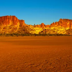 A landscape shot of Rainbow Valley, southwest of Alice Springs, in Australia’s Northern Territory. Spectacular red and yellow cliffs sit behind a stretch of red ground.