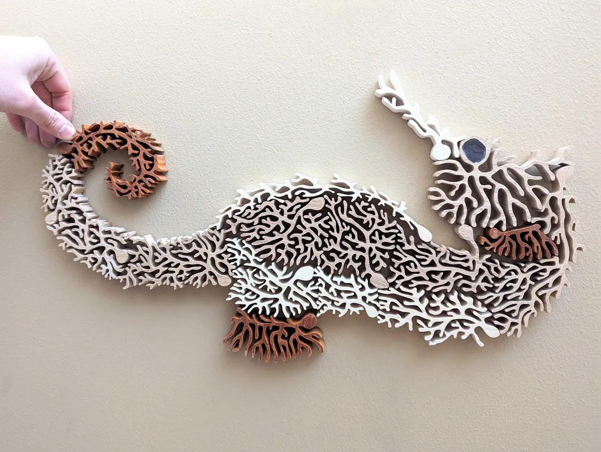 Image of a wooden sculpture comprised of multiple wooden neurons that form a seahorse.