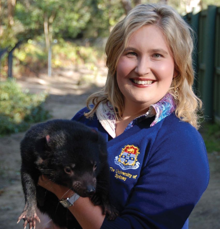 Image of Kathrine Belov holding a baby Tasmanian devil in her hands.