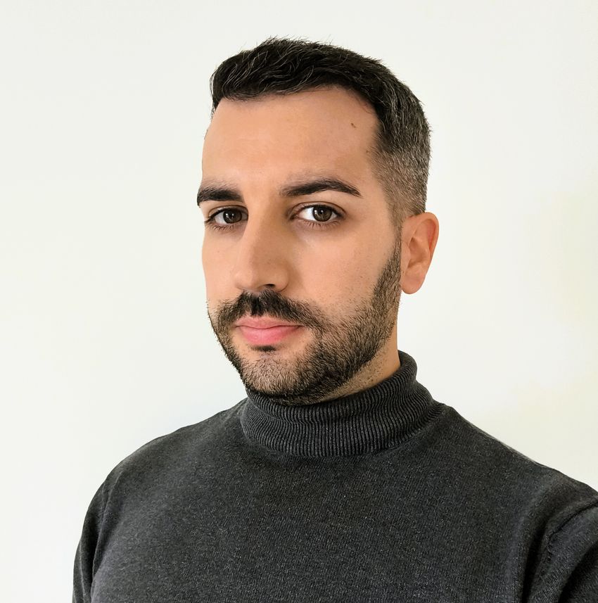 Emilio Mármol-Sánchez, wearing a dark grey heathered turtle neck, poses in front of a white background.
