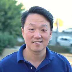 James Lim wears a blue shirt in a photo taken outdoors.