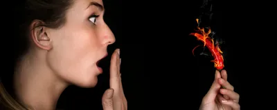 Person looks shocked, holding red chili pepper on fire. Some people like spicy food more than others. 
