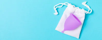 A menstrual cup and storage bag on a blue background