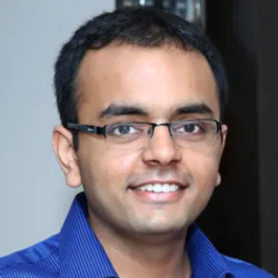 Ankur Gupta wears a blue shirt and glasses in a headshot photo.