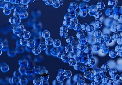 An illustration of small blue spheres representing electric field-controlled nanoparticles clustered together.