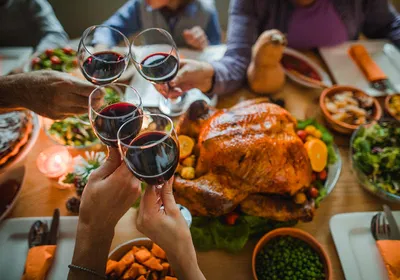 Group of people toasting with wine during Thanksgiving dinner at dining table. Better understanding of how alcohol affects the body and why some can’t resist it could help develop better treatments for alcohol use disorders. 