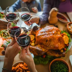 Group of people toasting with wine during Thanksgiving dinner at dining table. Better understanding of how alcohol affects the body and why some can’t resist it could help develop better treatments for alcohol use disorders. 