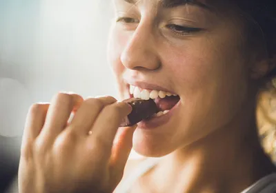 A woman eating a chocolate. Several women report craving sweets during the luteal phase of their menstrual cycle.