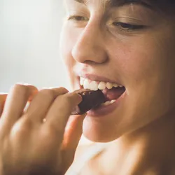 A woman eating a chocolate. Several women report craving sweets during the luteal phase of their menstrual cycle.