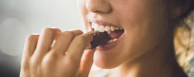 A woman eating a chocolate. Several women report craving sweets during the luteal phase of their menstrual cycle. A woman eating a chocolate. Several women report craving sweets during the luteal phase of their menstrual cycle.