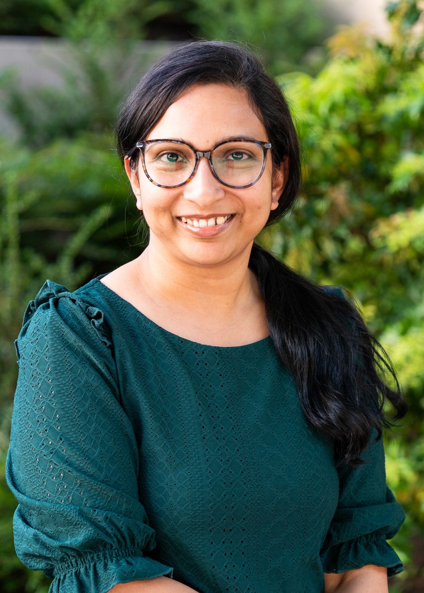 Damayanti Bagchi, wearing glasses and a dark green top, poses outdoors in front of plants. Damayanti Bagchi, wearing glasses and a dark green top, poses outdoors in front of plants.