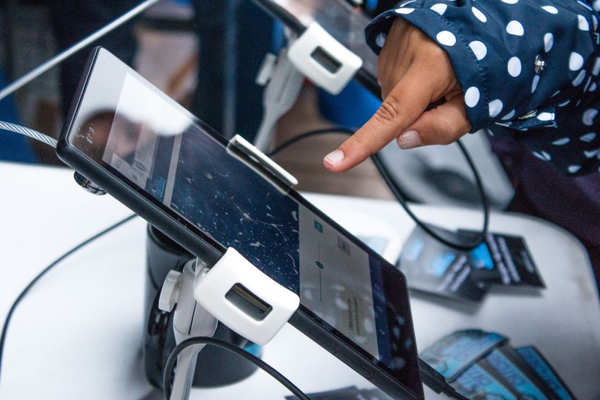 Image of a touch screen device with the Stall Catchers game on display. An index finger is pointed just above the screen.