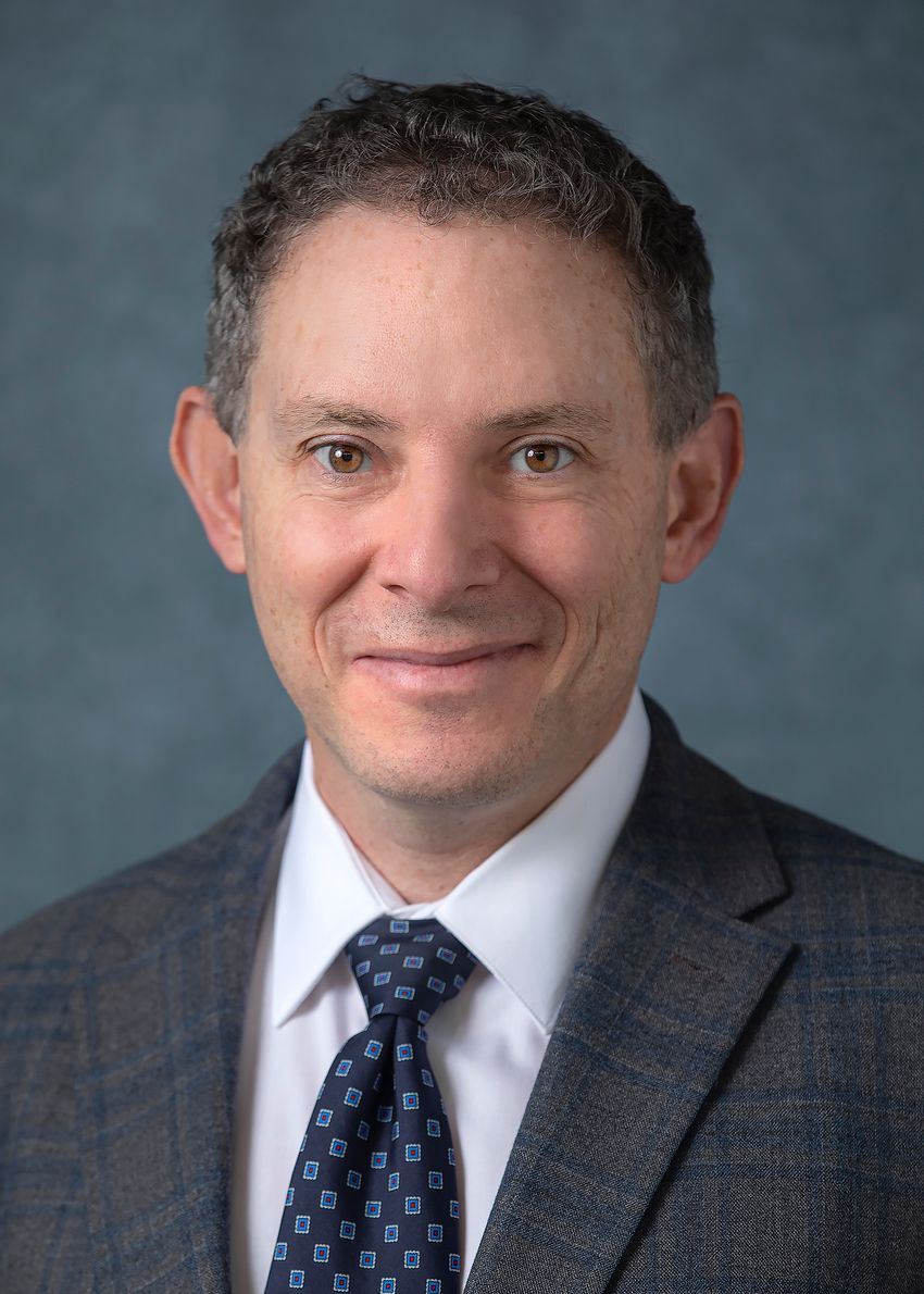 Ophir Klein, a developmental biologist at Cedars-Sinai Medical Center, wears a grey suit jacket against a dark background in a headshot photo.