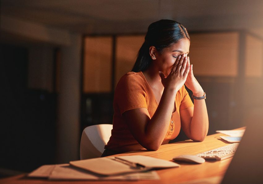 A woman holds her hands to her face looking stressed and anxious.