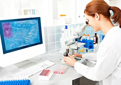 A female scientist analyzing samples through a microscope, engaged in histopathology studies in a laboratory environment.