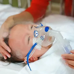 baby receives nebulization, signifying RSV infection that shapes allergic asthma risk later in life. 