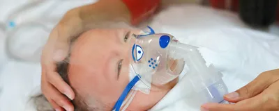 baby receives nebulization, signifying RSV infection that shapes allergic asthma risk later in life. 