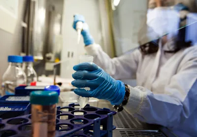 A person wearing a white lab coat carrying out cancer research in a lab.