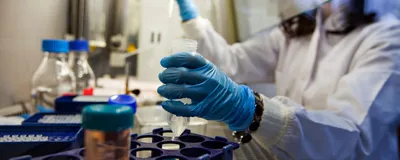 A person wearing a white lab coat carrying out cancer research in a lab.